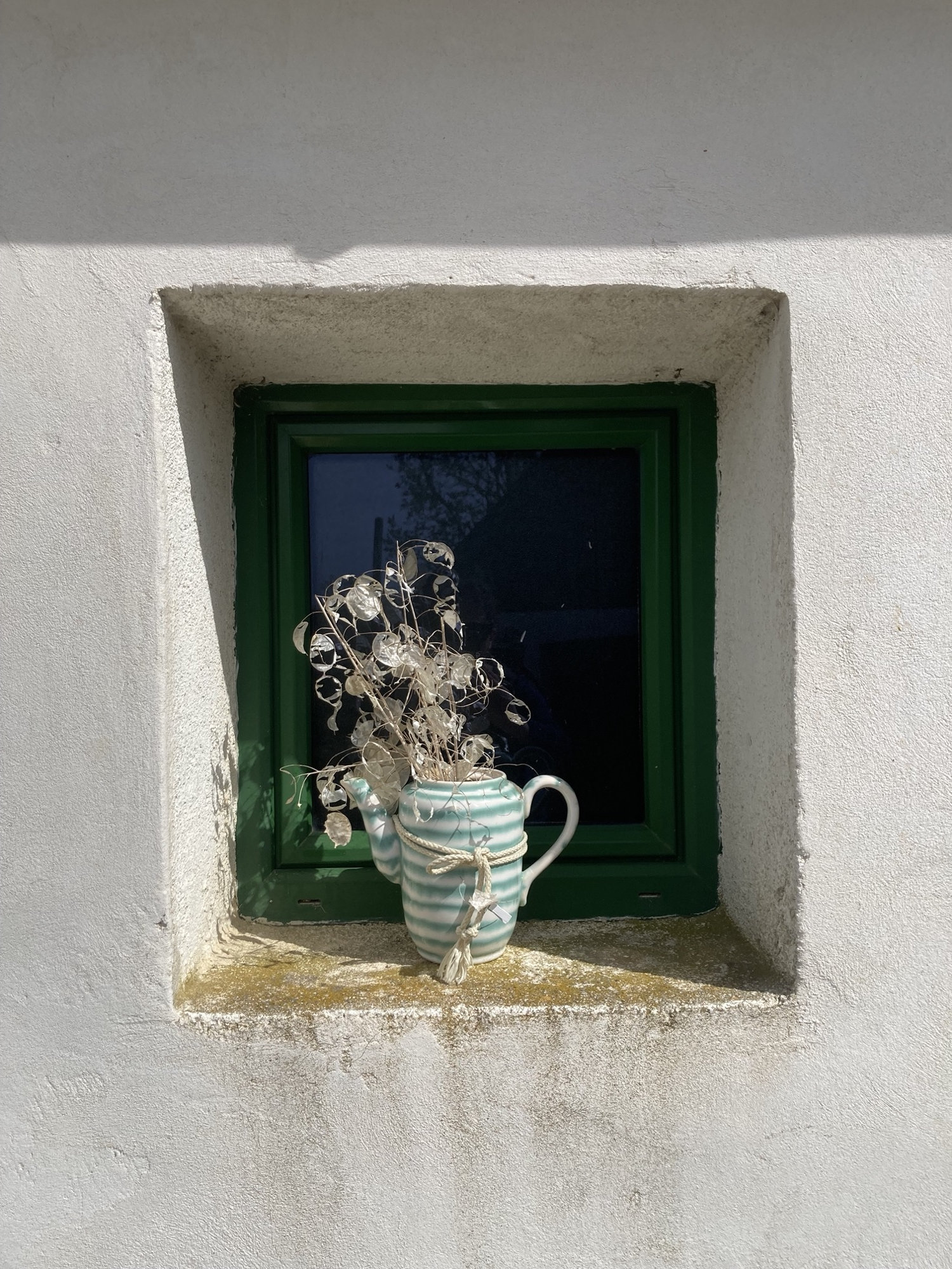 Fensternische eines Weinkellers, als Dekoration steht dort eine Keramikkanne mit getrockneter Pflanze darin