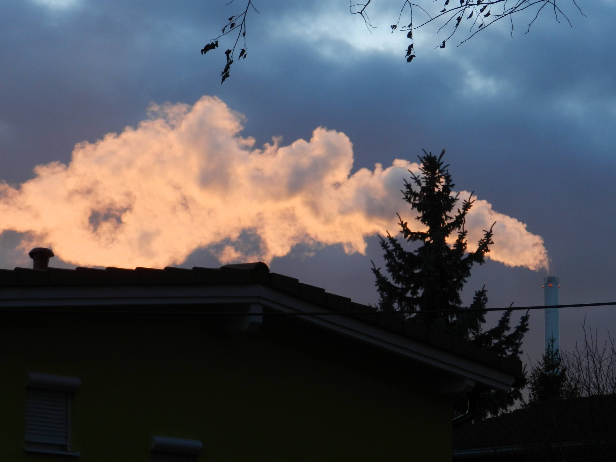 Rauchender Fabrikschlot im Sonnenuntergang
