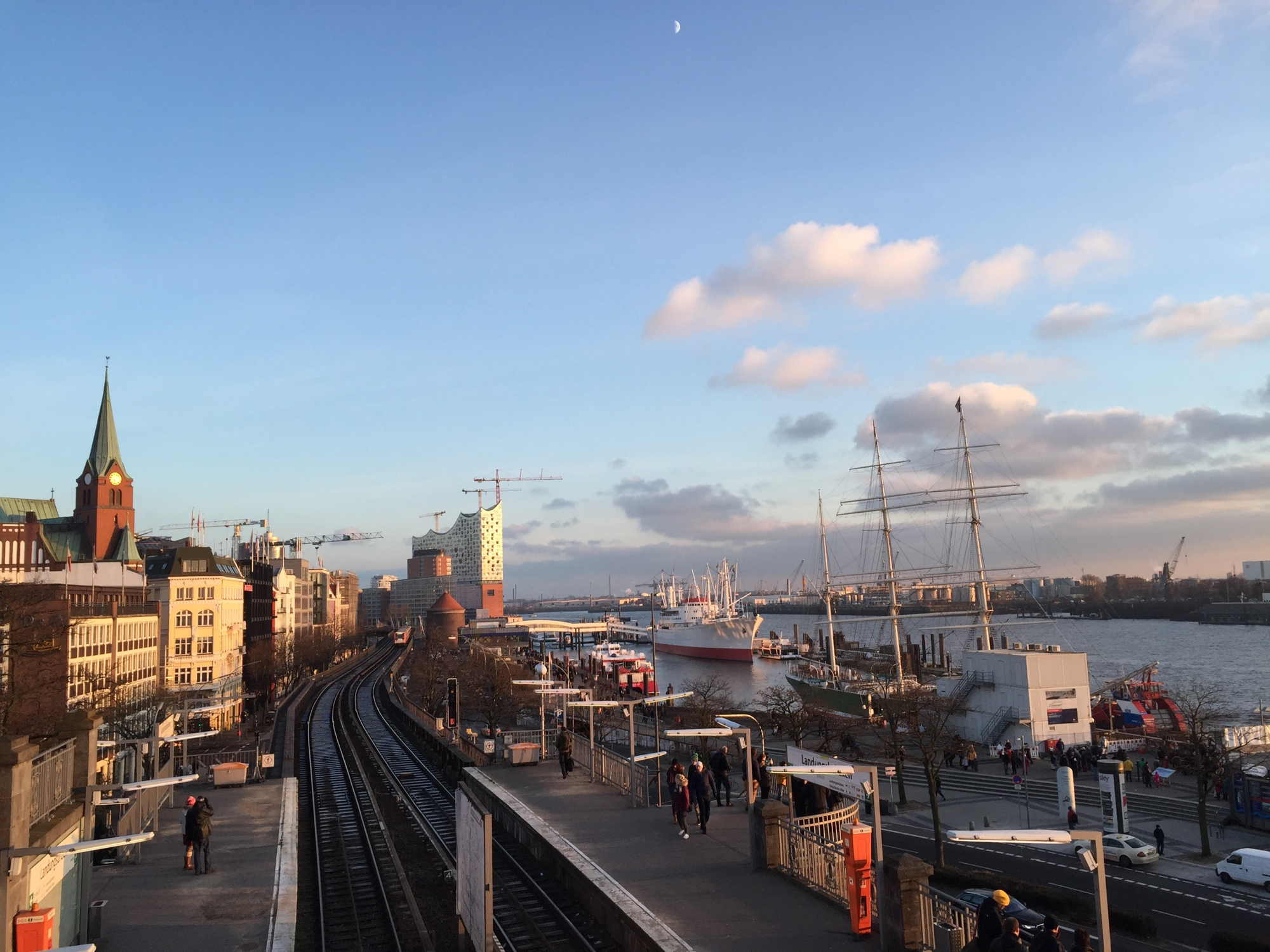 Blick von der Aussichtsplattform Stintfang über den Hafen mit U-Bahn-Gleis, Elbphilharmonie und Mondsichel am Himmel