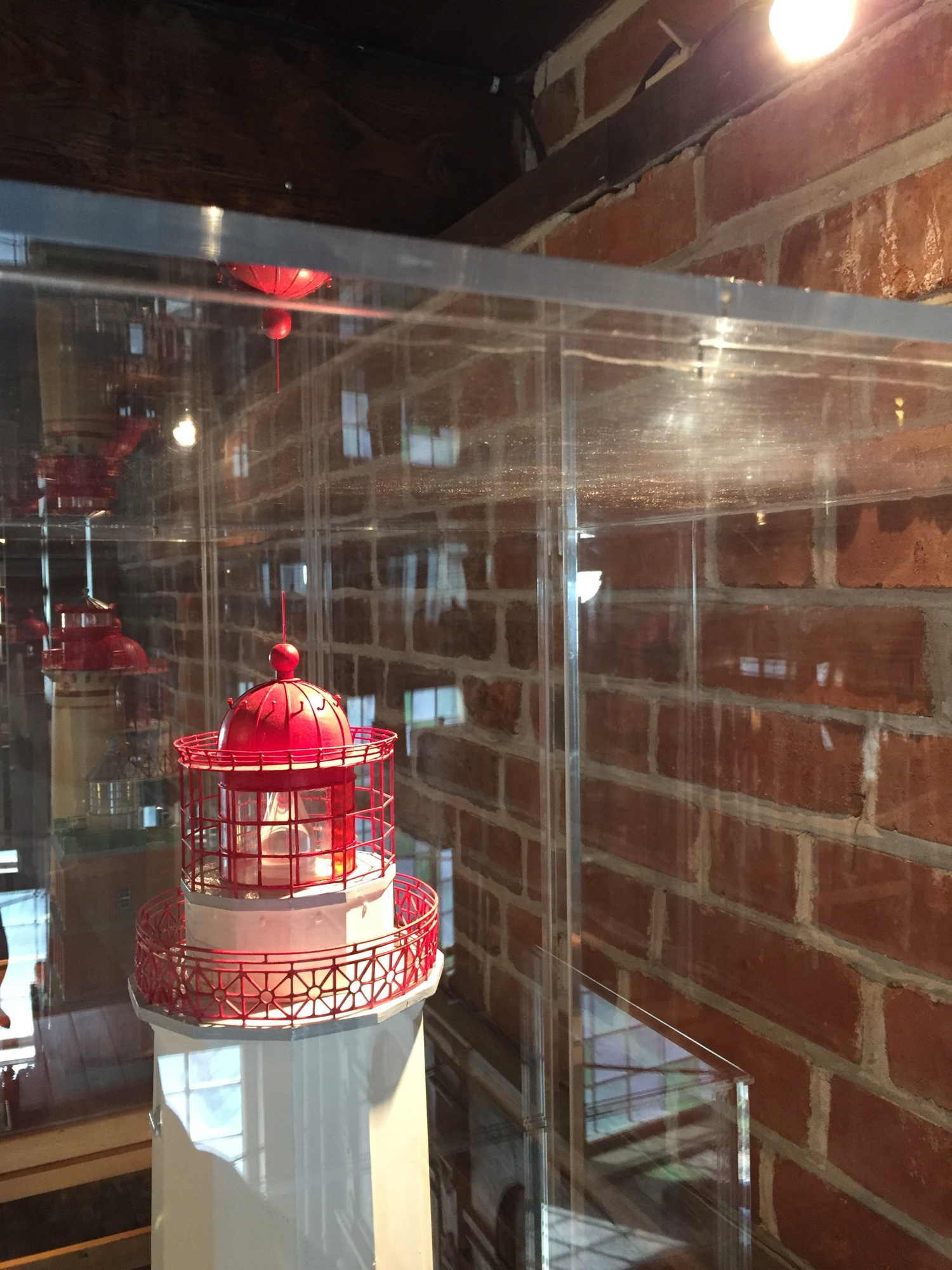 Modell eines Leuchtturms mit Lichtspiegelungen im schützenden Glaskasten