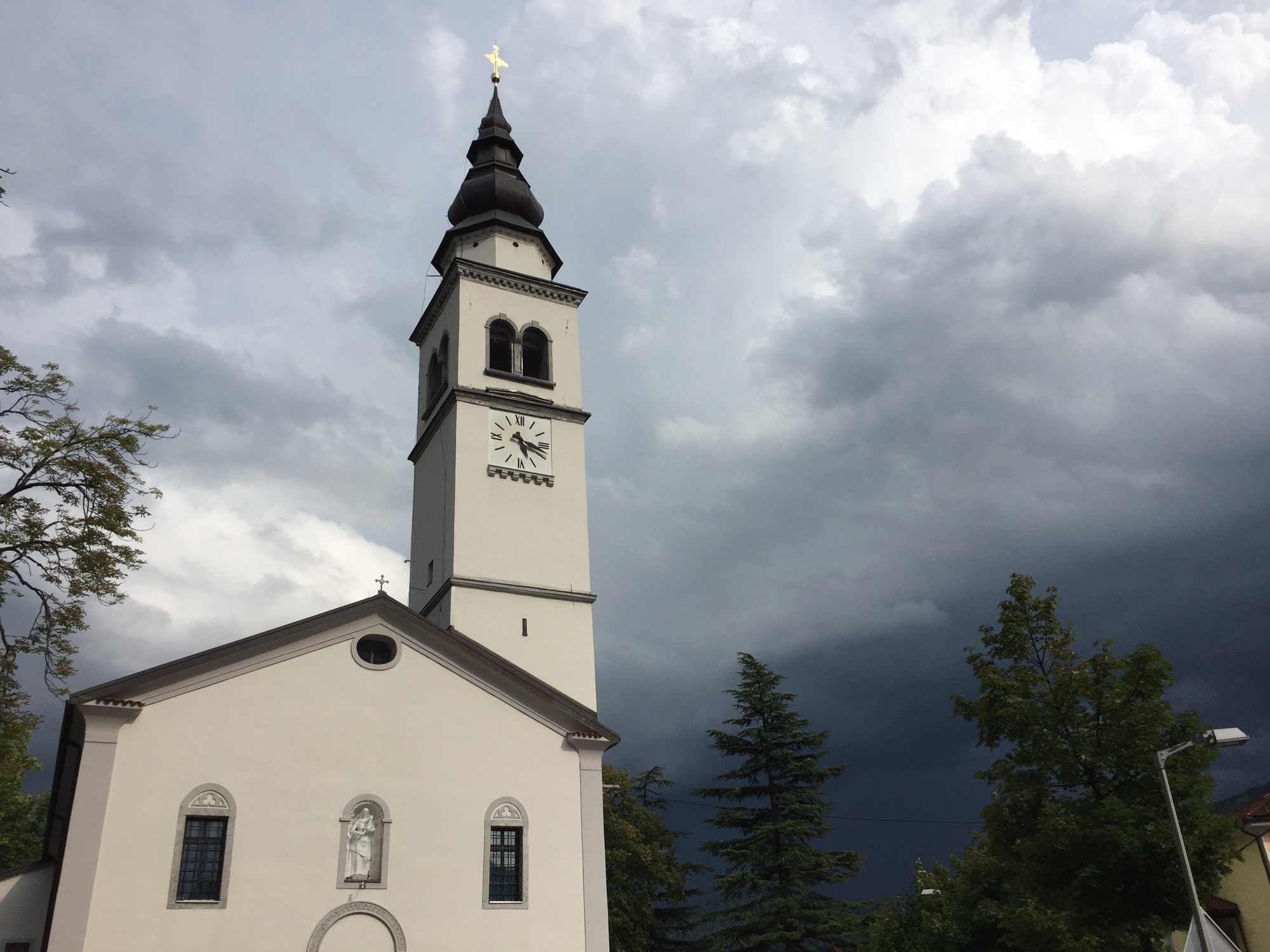 Kirche in Tolmin, mit dramatischen Gewitterwolken im Hintergrund