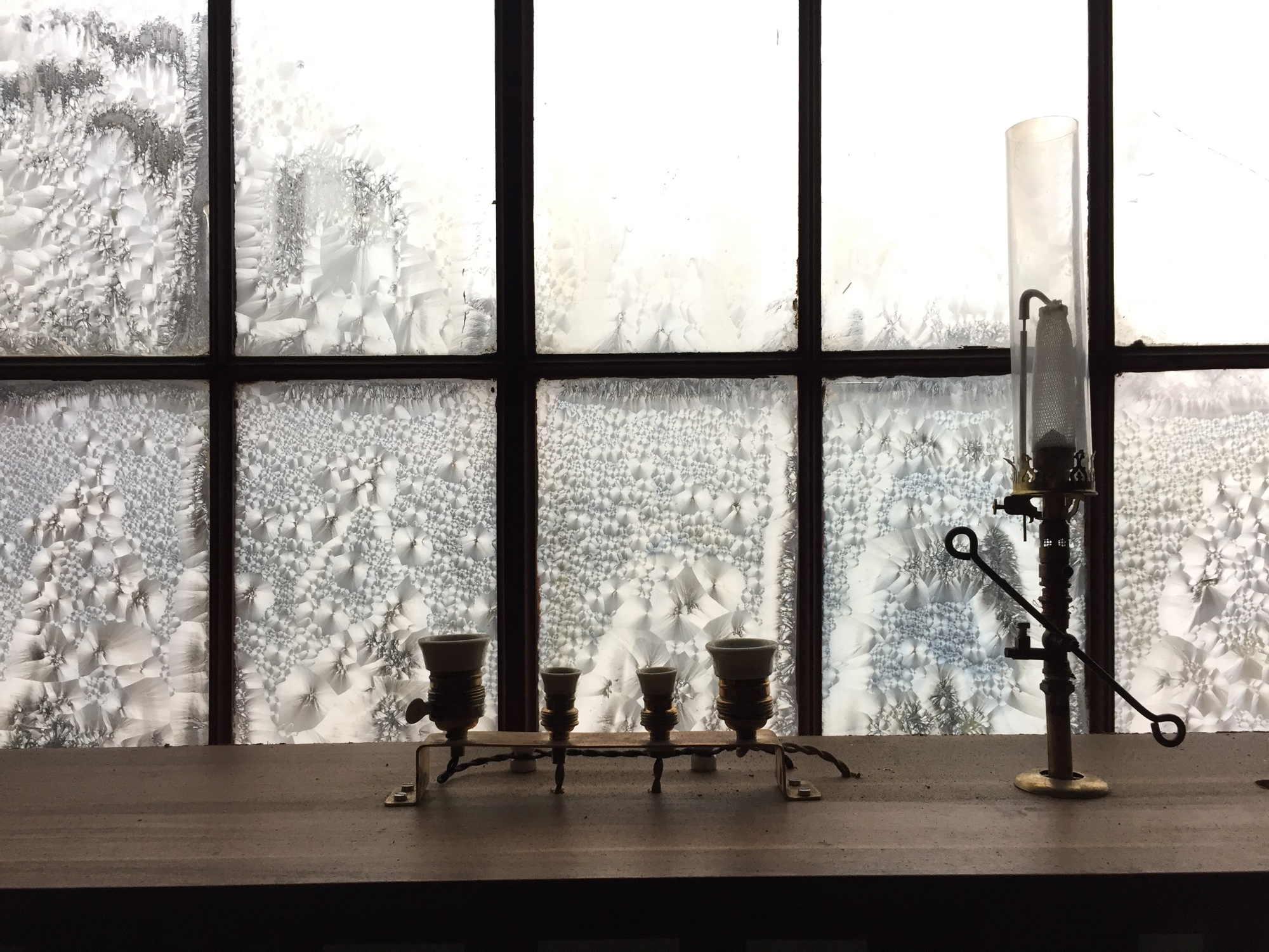 altmodische Gaslampen vor einem Fenster mit Eisblumen