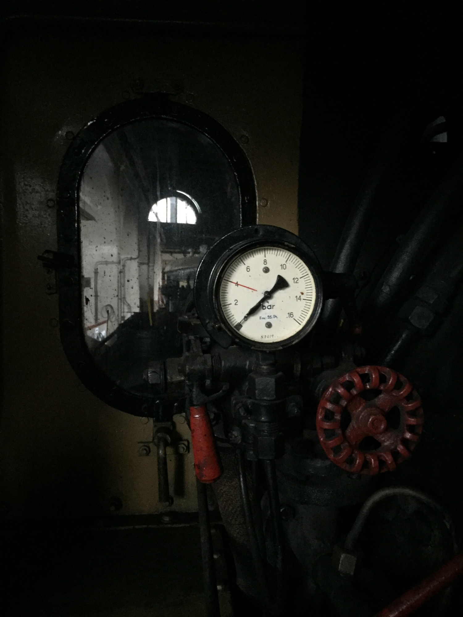 Druckmesser in einer Lokomotive vor einem Fenster, im Hintergrund ein weiteres Fenster, das Tageslicht in die Halle lässt