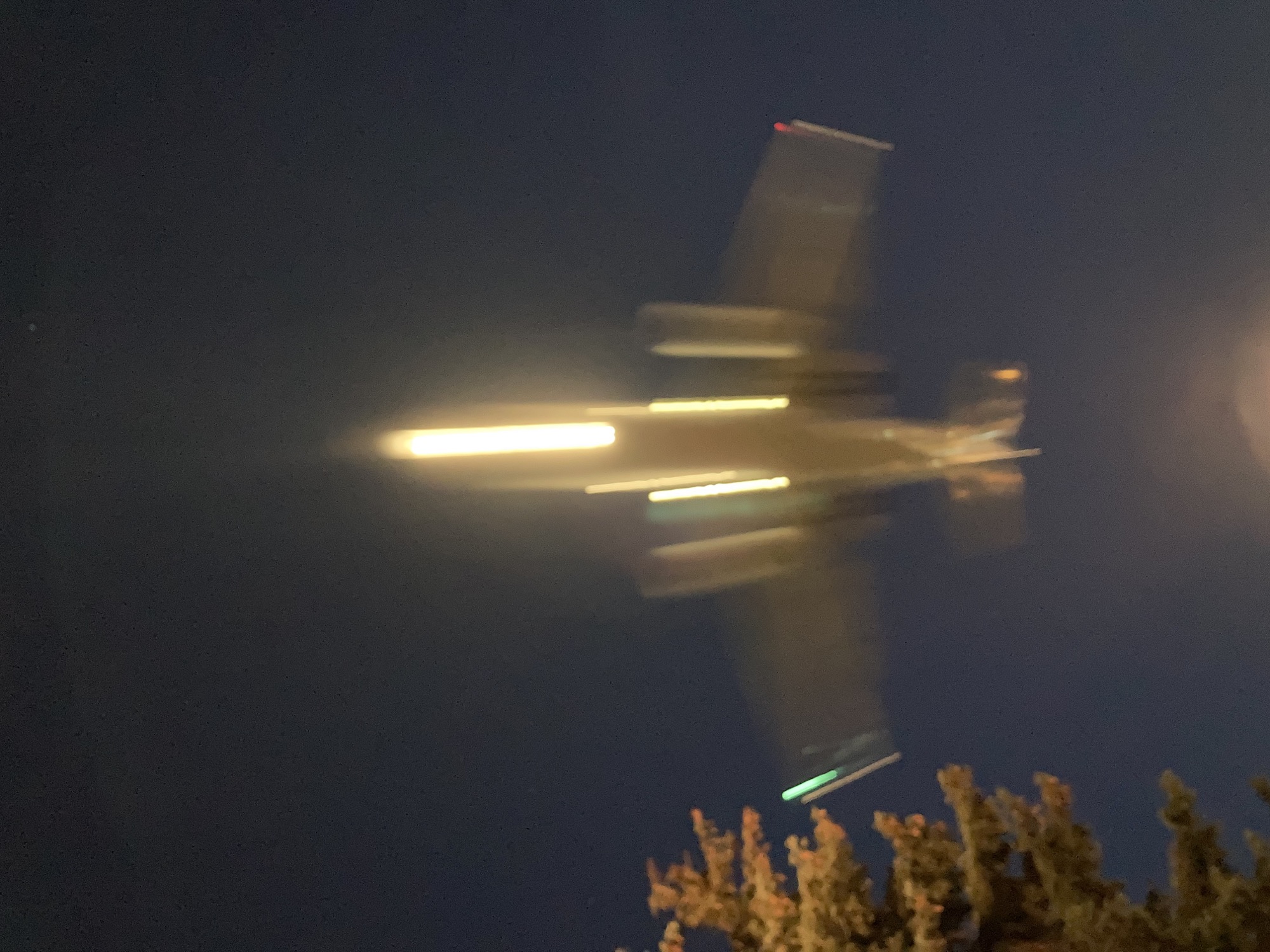 Flugzeug in der Einflugschneise in der Dämmerung, von unten gesehen, Bewegungsunschärfe