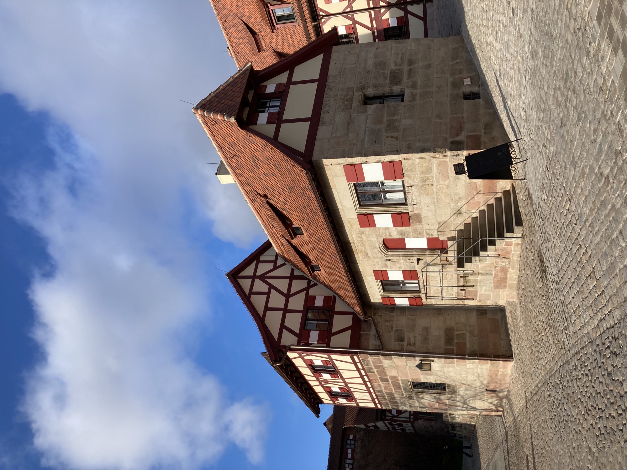 restauriertes Gebäude im Burghof, Fachwerk mit rot-weiß-roten Fensterläden