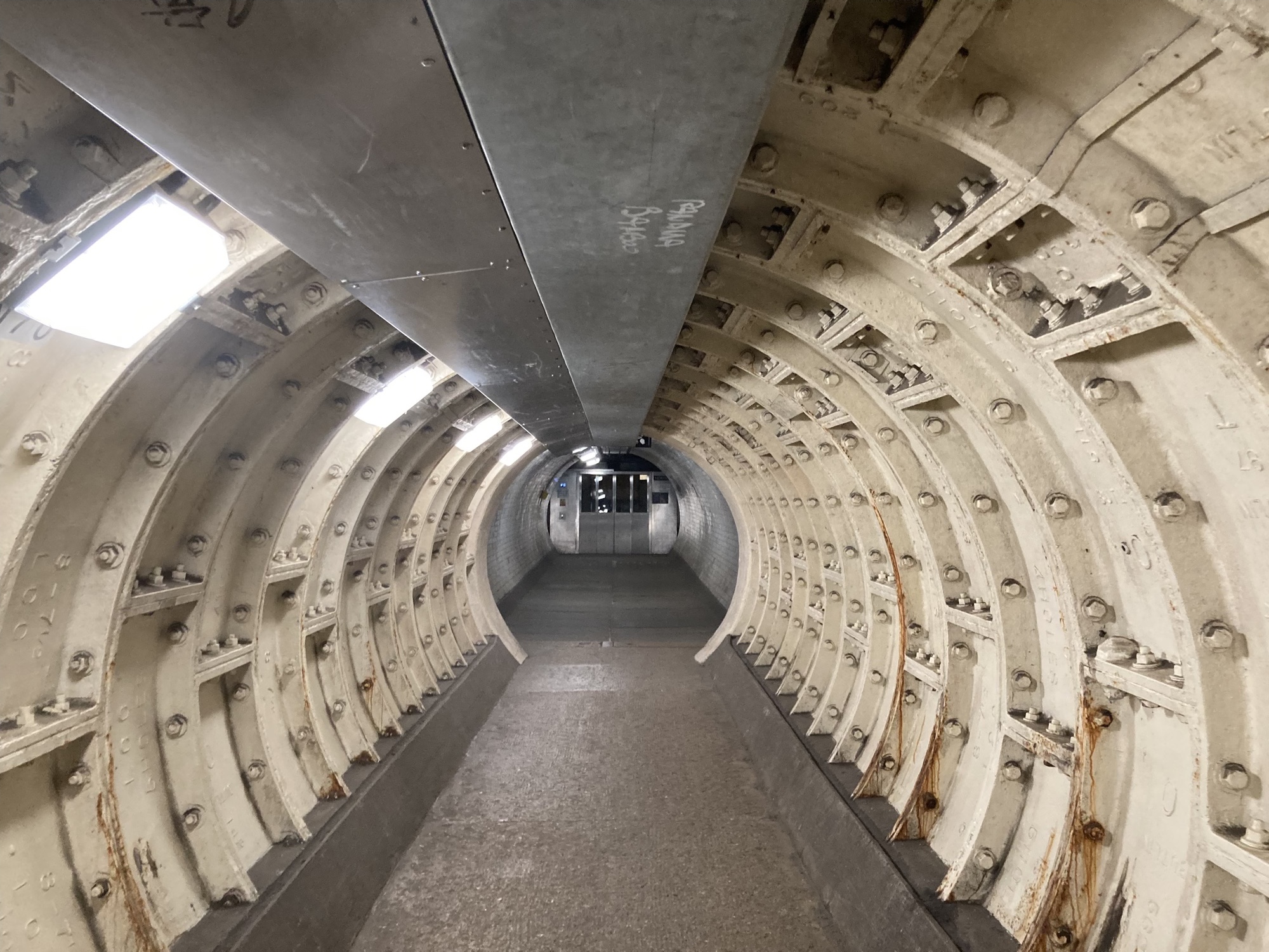Tunnelblick in den nördlichsten Abschnitt des Greenwich Foot Tunnel, der im zweiten Weltkrieg beschädigt und später mit Metallringen repariert wurde, am Ende des Tunnels ein Aufzug außer Betrieb