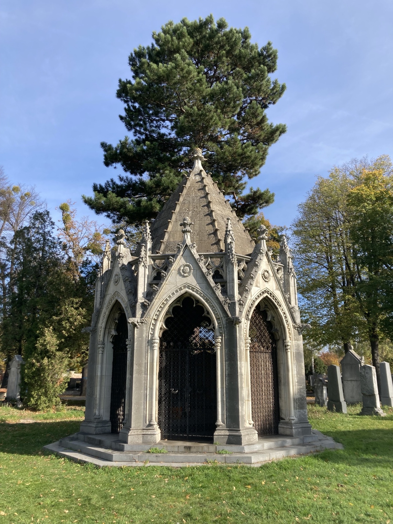 Mausoleum mit sechs-eckigem Grundriss, die Türen sind kunstvoll vergittert und mit verspielten Ziergiebeln versehen, Herbstsonne