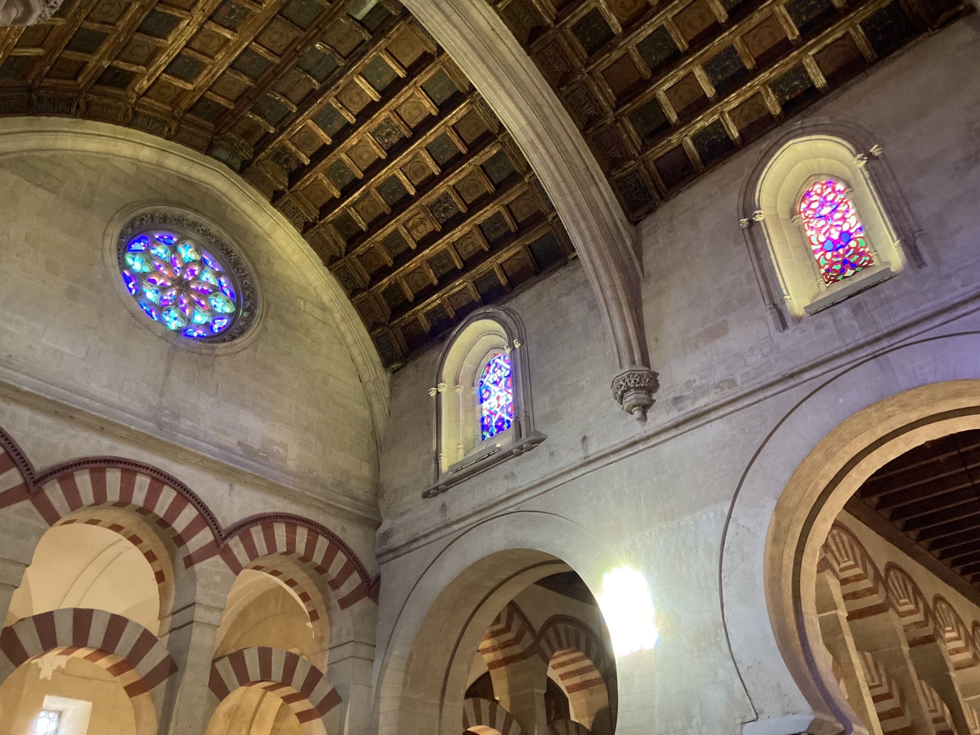 Architekturdetails in der Moschee-Kathedrale, bunte Mosaikglasfenster, durch die Licht herein scheint, die Holzdecke besteht aus quadratischen Einzelteilen, darunter mit Bogenverbindungen gekrönte Säulen