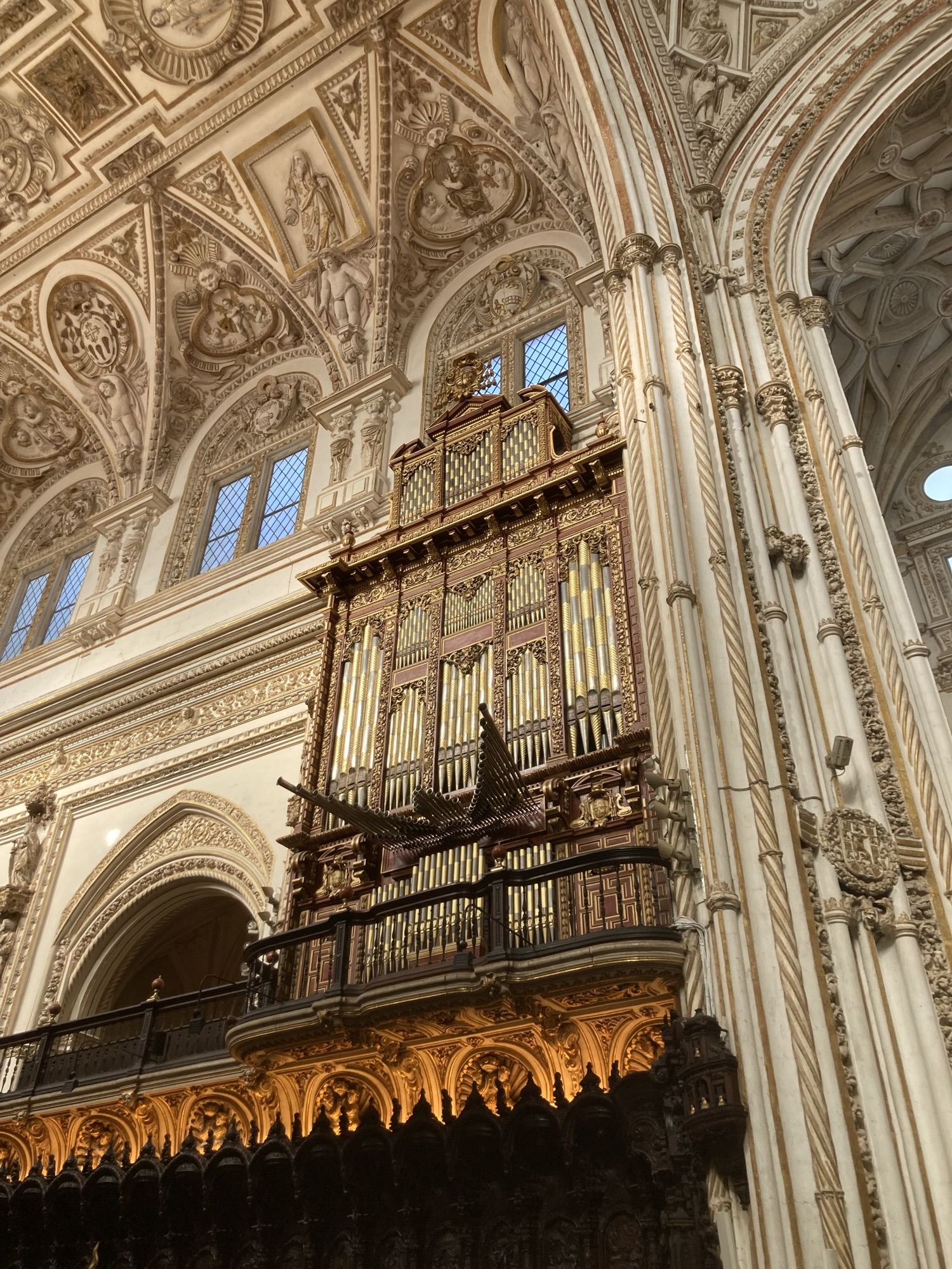 gewaltige Orgel im Kirchenschiff, darüber sind Teile der Deckenverzierungen zu sehen, darunter die Sitzbänke der Priester, aus dunklem Holz geschnitzt, mit hohen Lehnen