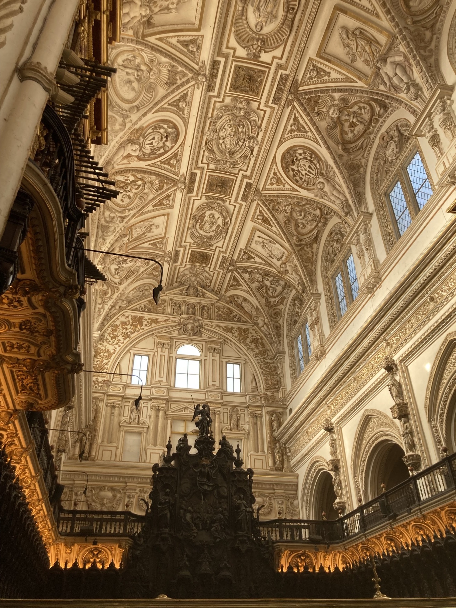 Blick Richtung Decke des Kirchenschiffs, unten die geschnitzten hölzernen Sitzbänke der Priester, oben die reich verzierte Decke