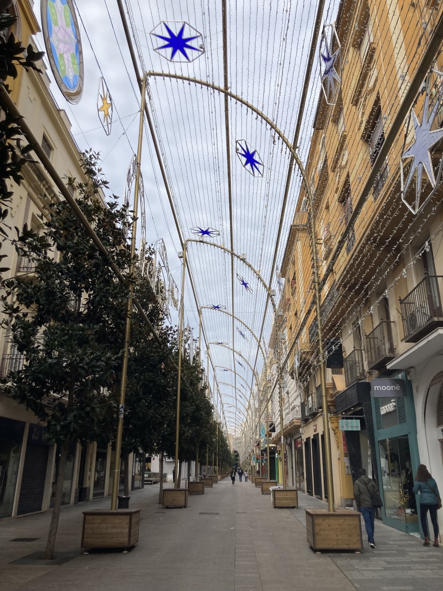 Einkaufsstraße im Zentrum von Córdoba, überspannt von einer Weihnachtsdekoration, die jedoch im Nachmittagslicht nicht leuchtet