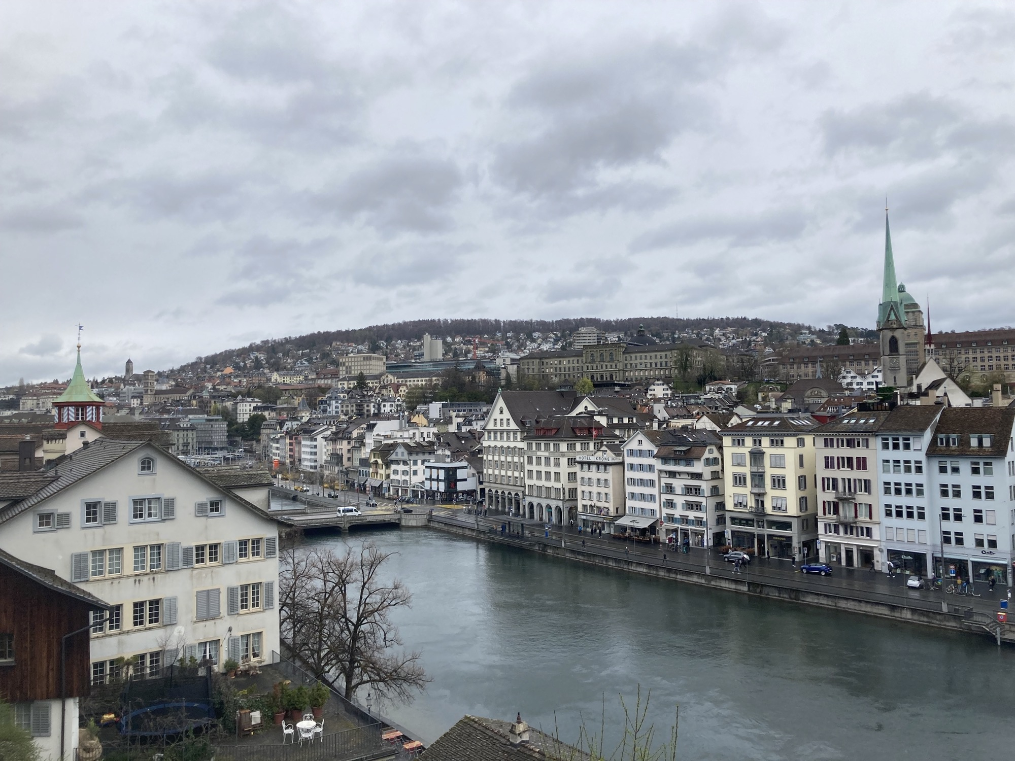 Blick vom Lindenhof über den Fluss Limmat auf die dahinter liegende Innenstadt mit Zunfthäusern, der Himmel ist bewölkt, düstere Stimmung