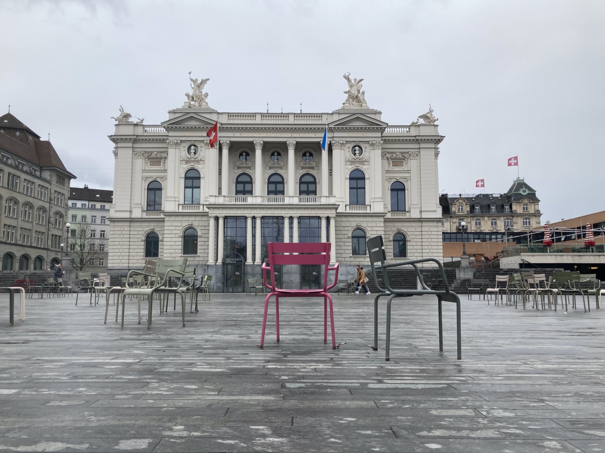 Opernhaus Zürich, davor zufällig angeordnete Gruppen von Metallsesseln, zentral in der Mitte steht ein vereinzelter rosafarbener Sessel