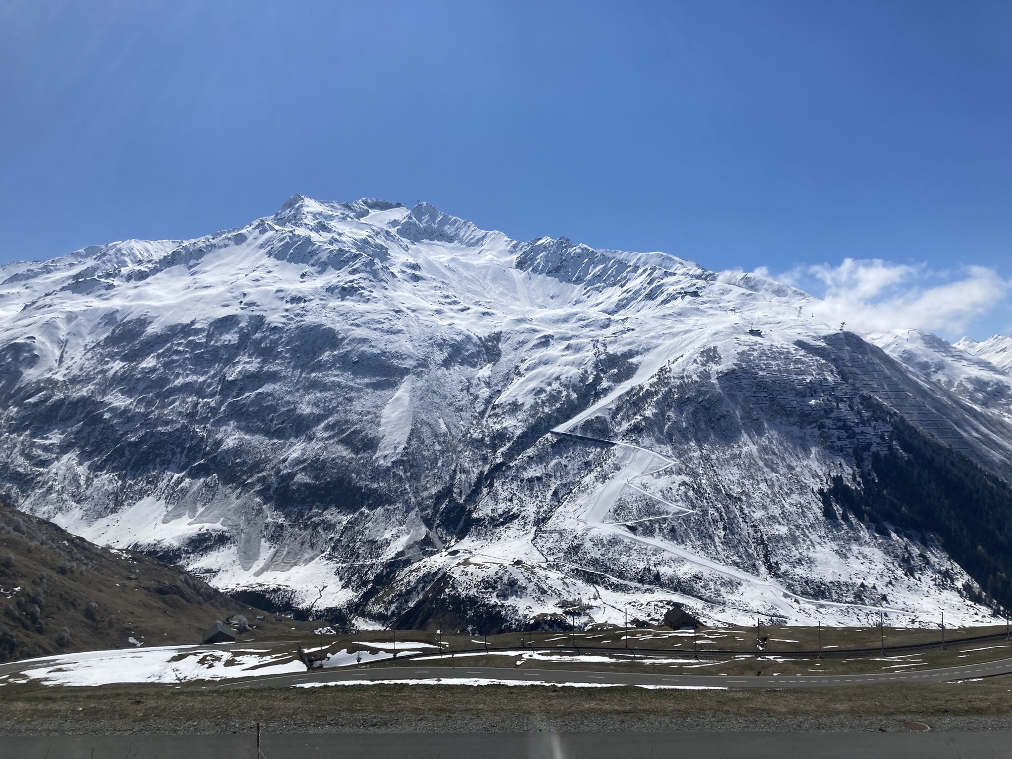 schneebedeckte Bergkette vor strahlend blauem Himmel, eine Skipiste kreuzt die ansonsten scheinbar unberührten Berge