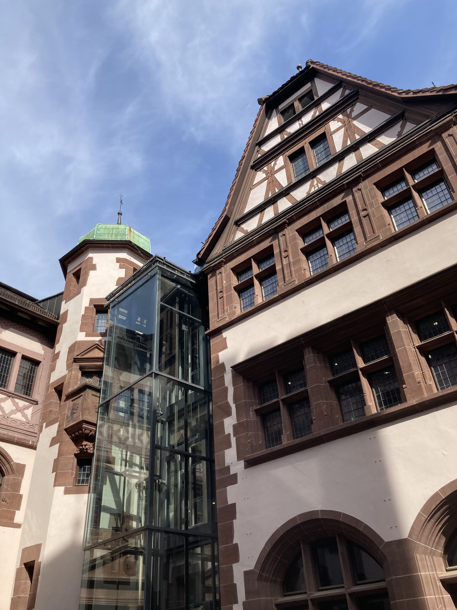 Innenhof des Neuen Rathauses, neben altmodischen Ziegelfassaden und Fachwerkdach ist ein gläserner Außenlift angebaut