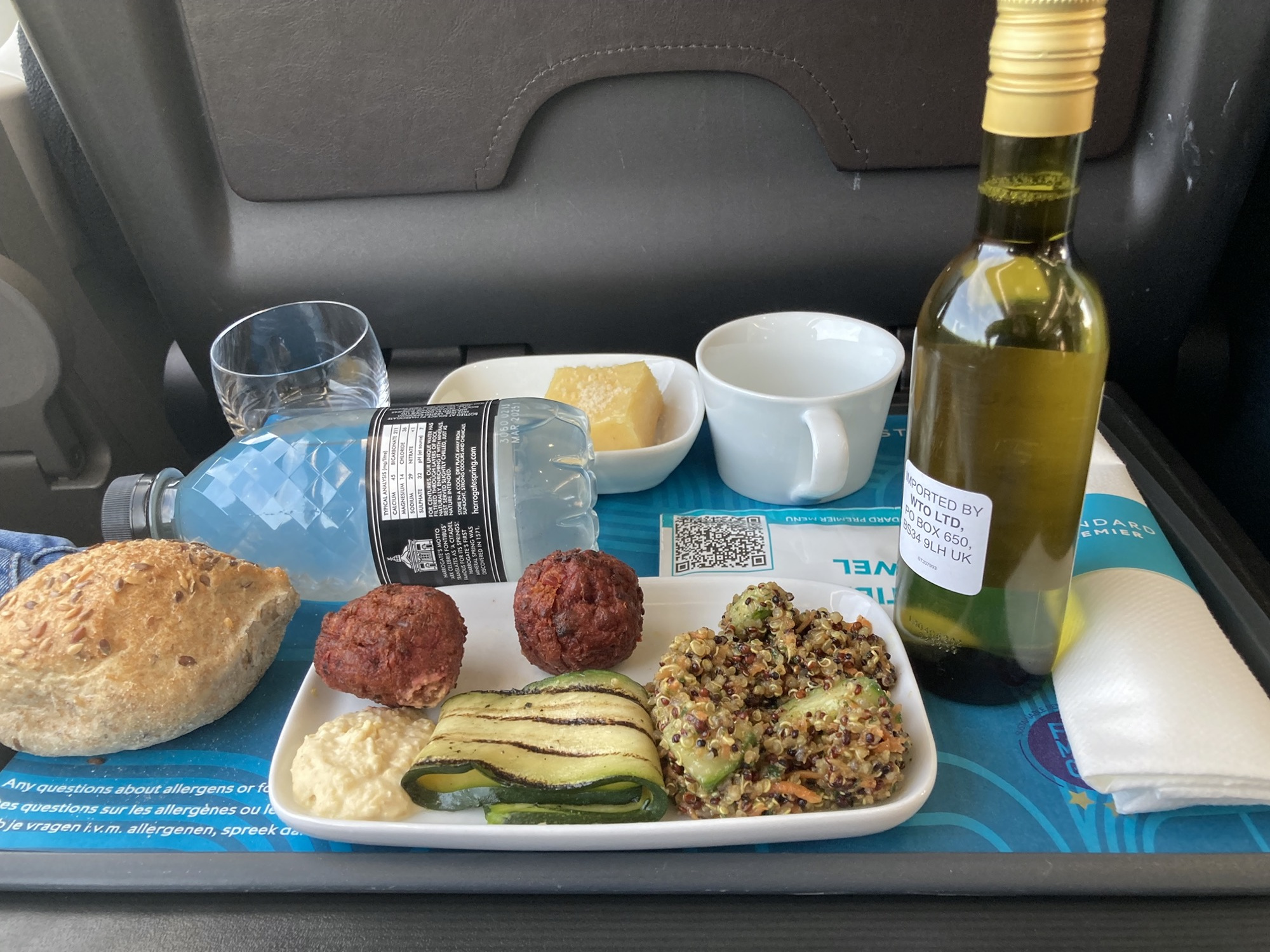 Tablett mit Verpflegung im Eurostar, eine kleine Flasche Wasser, eine kleine Flasche Wein, ein Glas, ein Brötchen, ein Teller mit Falafel, Hummus, Zucchini und Quinoagemüse, eine kleine Schale mit einem Dessert