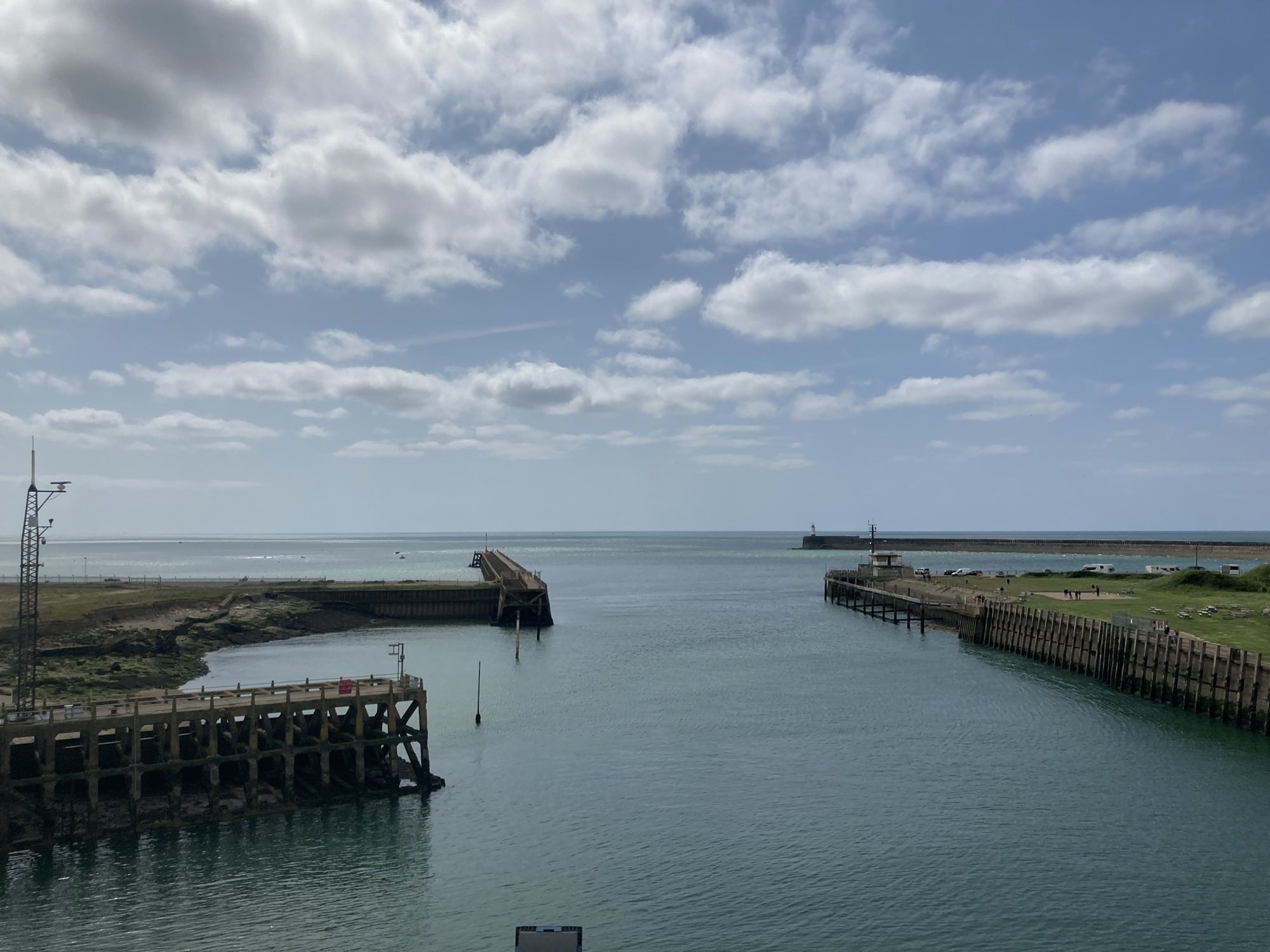 Ausblick über den Hafen von Newhaven, links ein Steg der ins Wasser hinein ragt, rechts eine runde menschengemachte Bucht, mit einem erahnbaren Leuchtturm am Ende