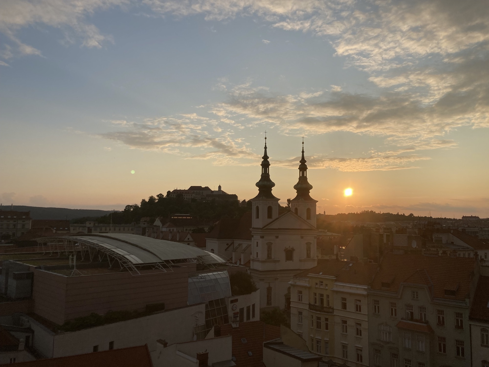 Ausblick vom Turm des Rathauses, zentral der Festungsberg und das davor gelegene Kloster, rechts dahinter die untergehende Sonne