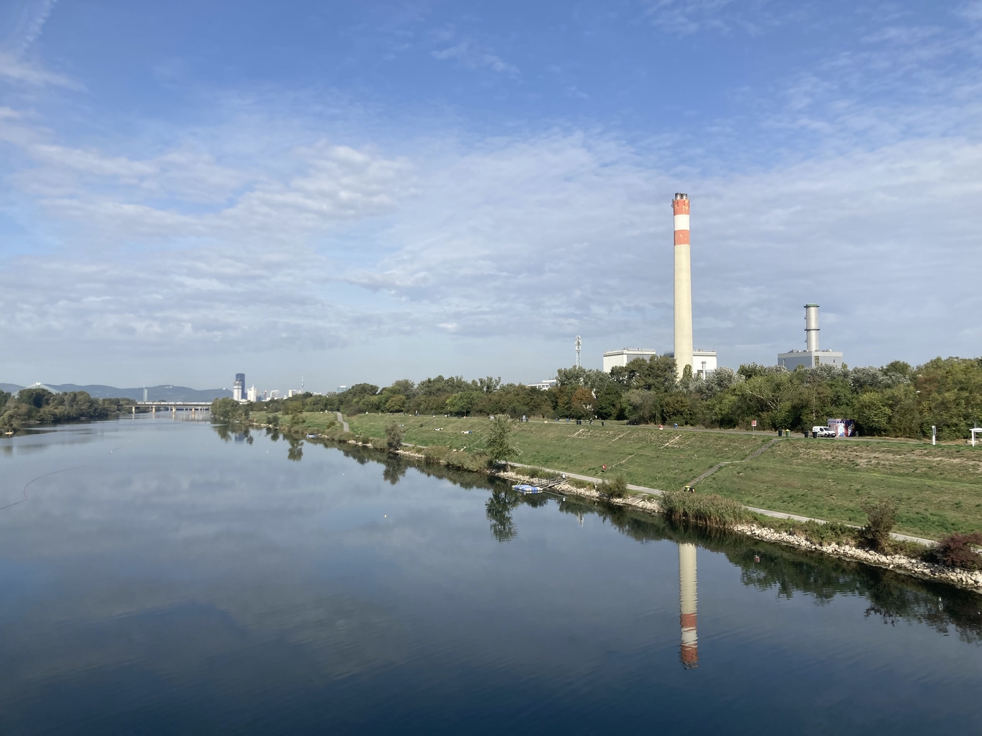 Blick über die Donau, rechts im Bild ein Fabrikschlot, der sich auch im Wasser spiegelt