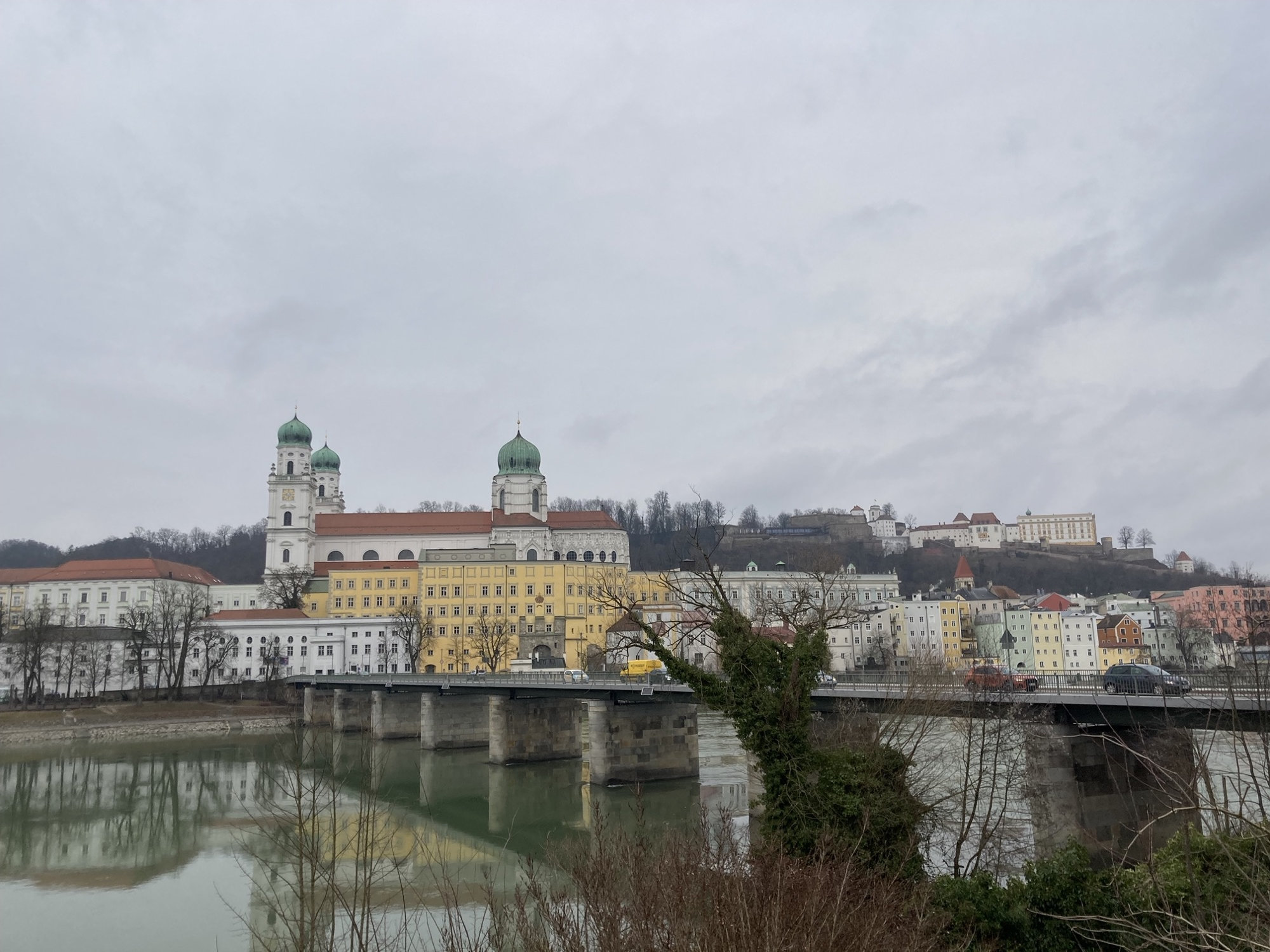 Ausblick auf die Altstadt von Passau vom südlichen Inn-Ufer, im Vordergrund ruht die Marienbrücke auf mehreren massiven Steinsäulen, im Hintergrund sind die drei Kuppeln des Dom St. Stephan zu sehen