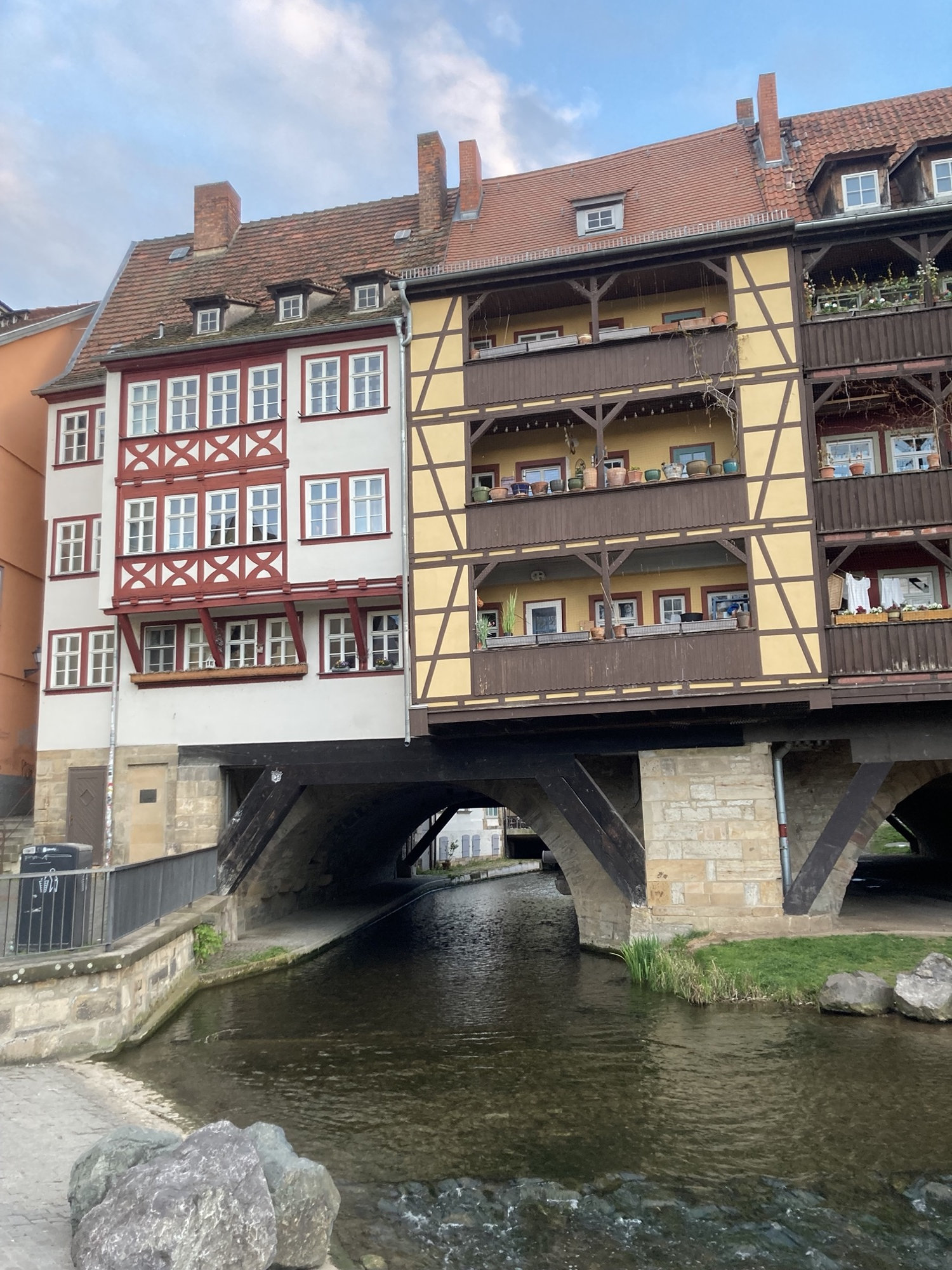 Krämerbrücke, altmodische Häuser mit Fachwerkbalkonen, sie stehen auf einer Steinbrücke, unter der ein Fluss dahin plätschert