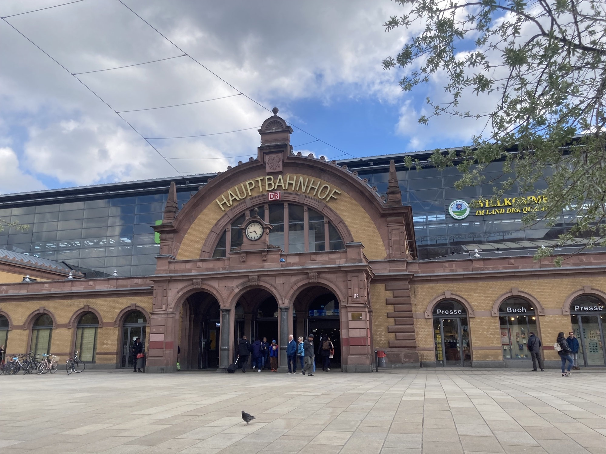 Hauptbahnhof Erfurt, ein Ziegelgebäude in unterschiedlichen Brauntönen, der Haupteingabg hat drei Torbögen, darüber eine Bahnhofsuhr und ein höherer Bogen mit dem Schriftzug „Hauptbahnhof¶
