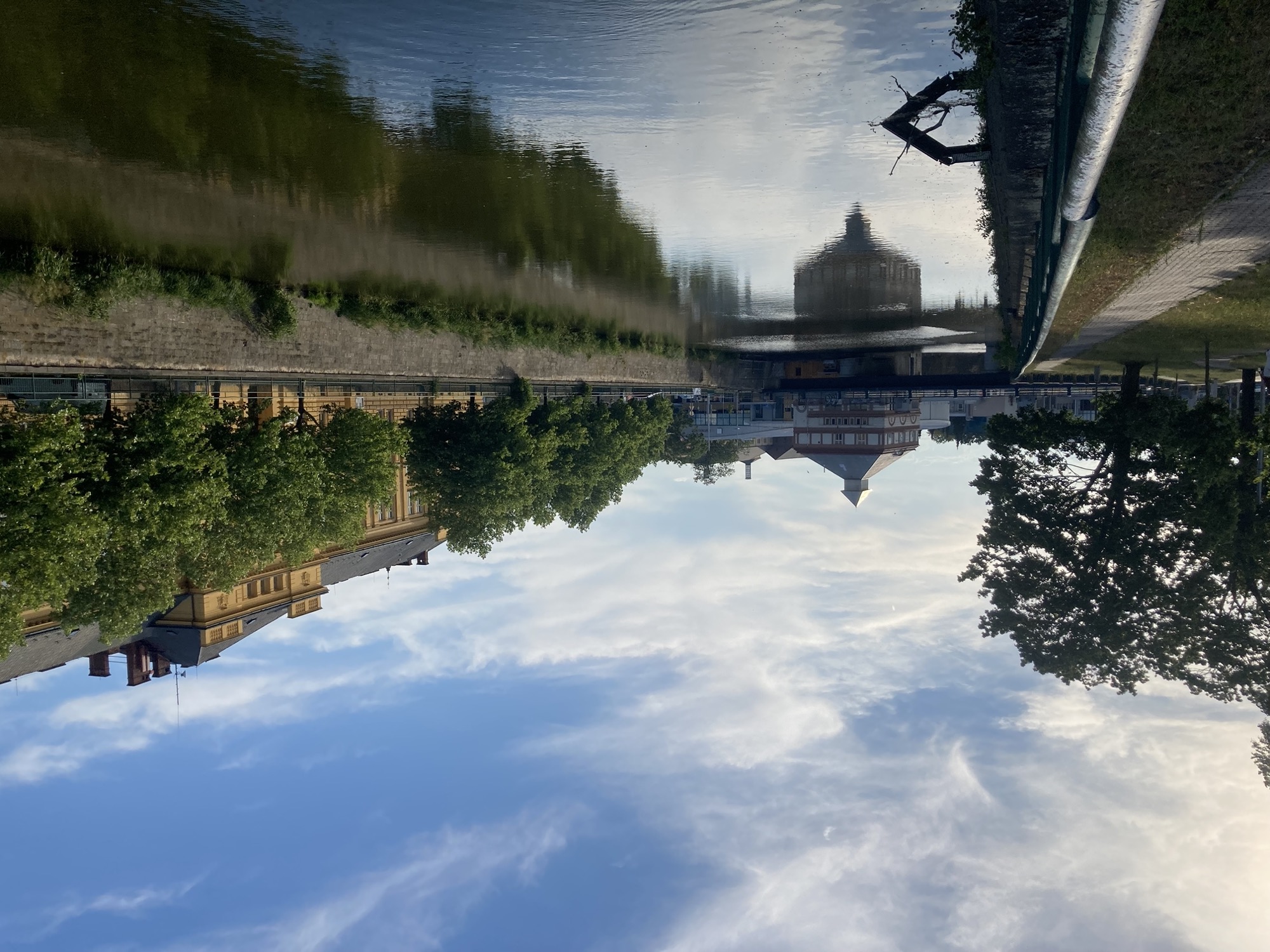 Blick über den Fluss, die Brücke und das Gebäude im Hintergrund spiegeln sich im Wasser