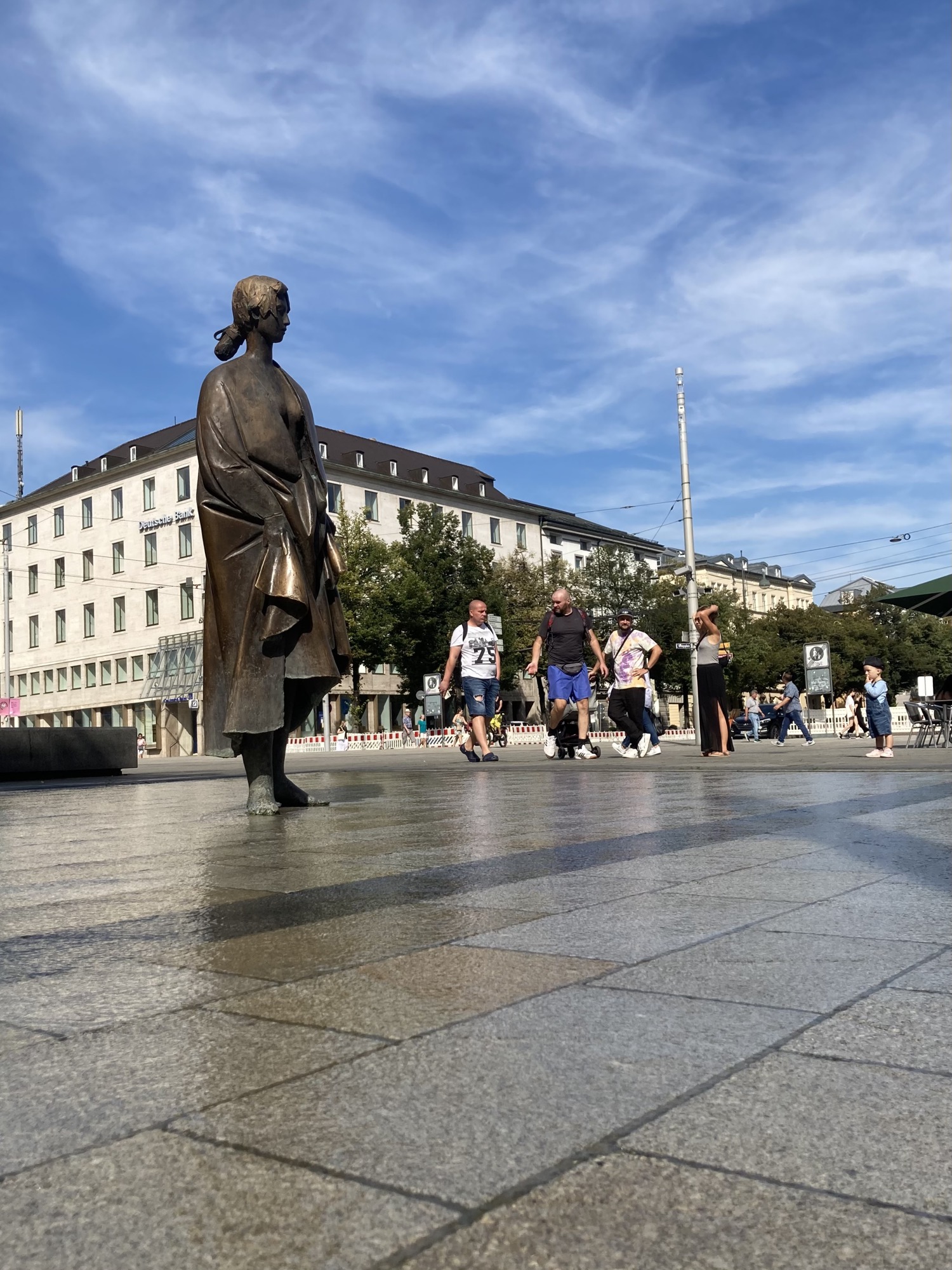 Manzù-Brunnen, eine weibliche Metallfigur mit bloßen Füßen steht auf einer Wasserfläche, es wirkt, als würde die Figur auf dem Wasser gehen