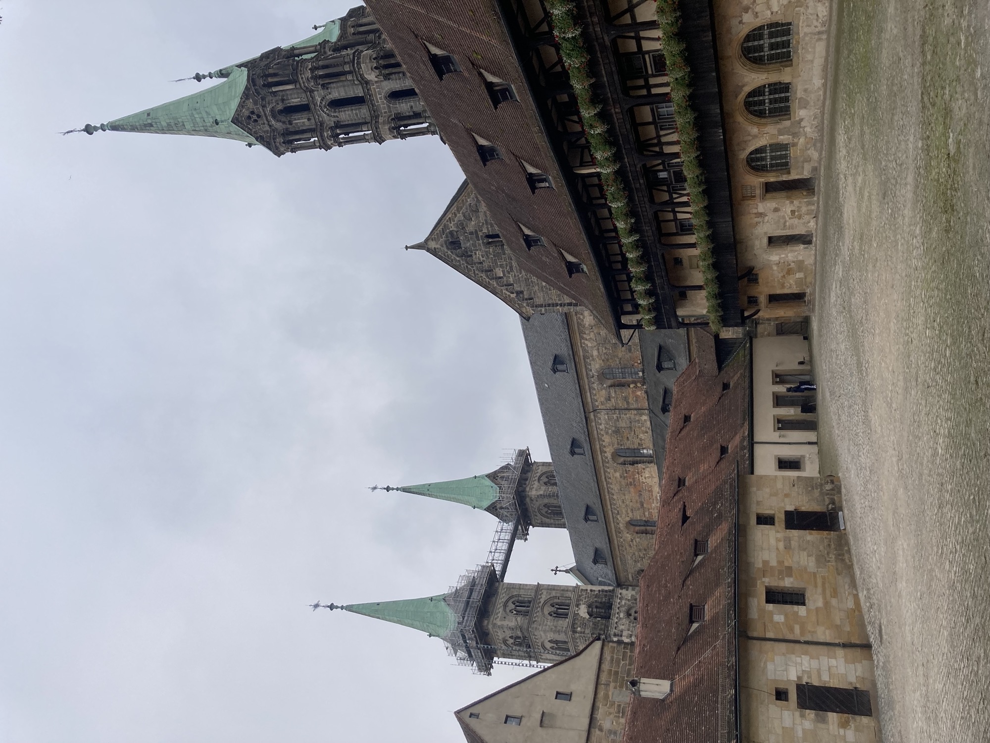 Innenhof des Gebäudes Alte Hofhaltung, der Boden ist gepflastert, das Gebäude rechts hat zwei Stockwerke mit blumengeschmückten Galerien davor, hinter dem Gebäude ragen die Türme des Doms in den Himmel