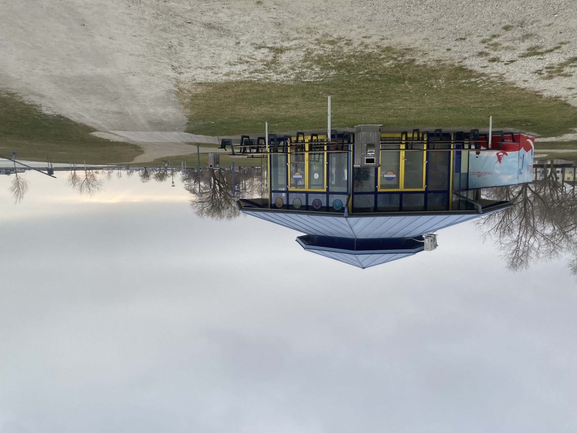 Snackhaus an der Strandpromenade, es ist Winter, der Boden braun und kahl, der Himmel grau, rund um das geschlossene Snackhaus stehen Picknickbänke