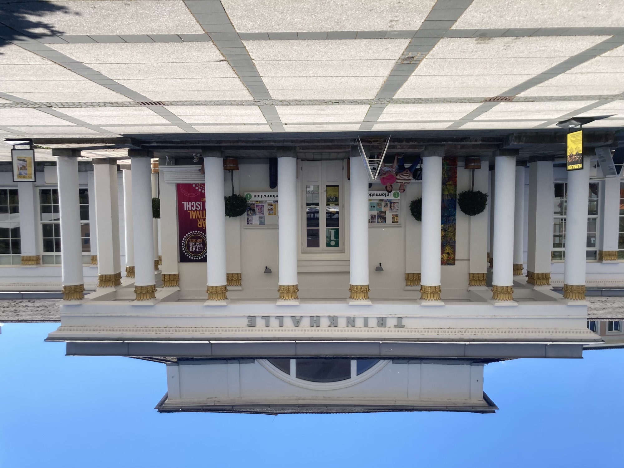 imposantes weißes, einstöckiges Gebäude, das Vordach wird von 8 Säuen mit goldener Verzierung gestützt, darüber das Wort „TRINKHALLE“
