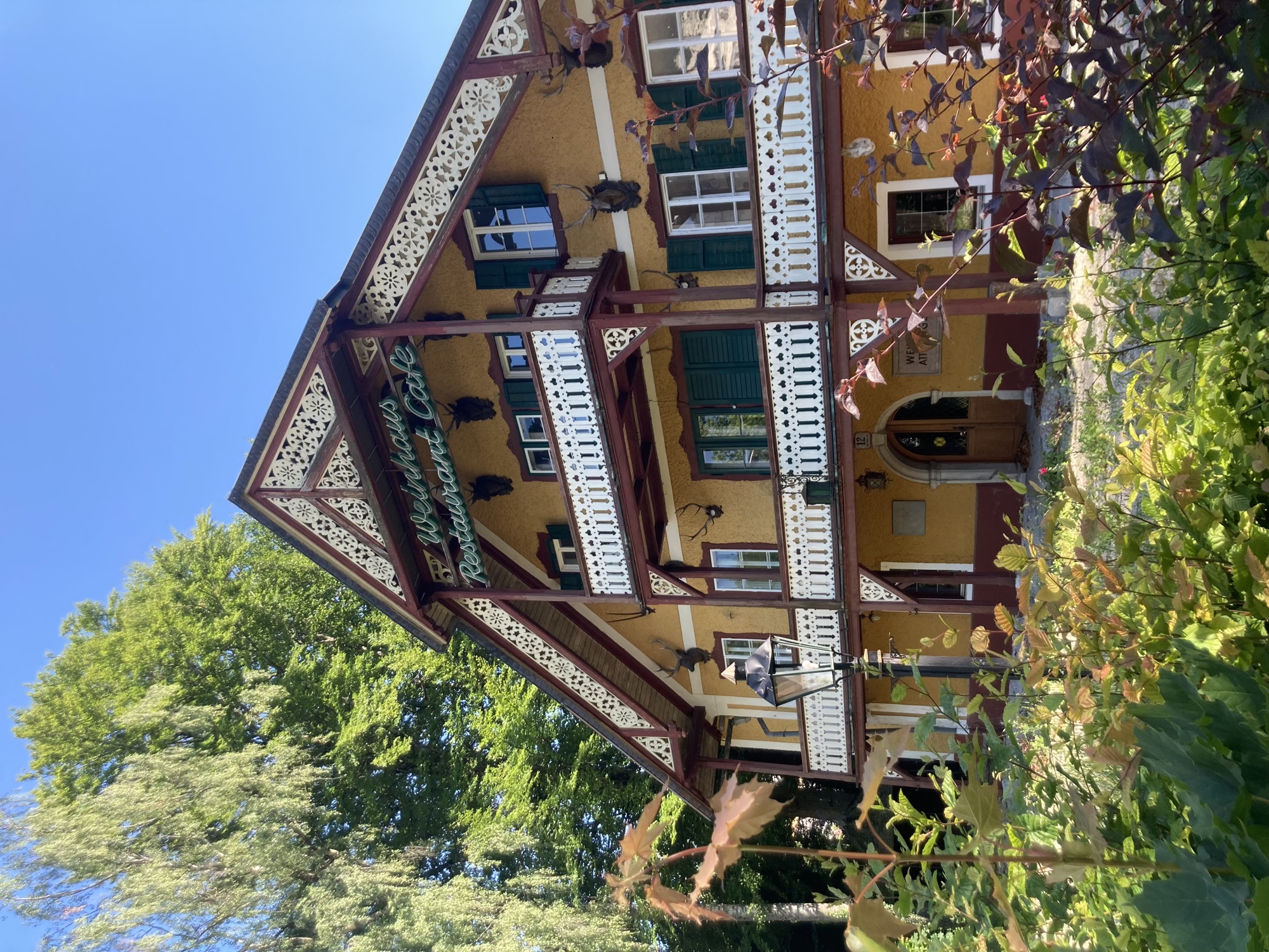 Haus mir der Aufschrift „Weinhaus Restaurant Cafe“, die Balkone und der Rand des Dachs sind weiß dekoriert, es sieht aus, als würden dort Häkeldeckchen hängen