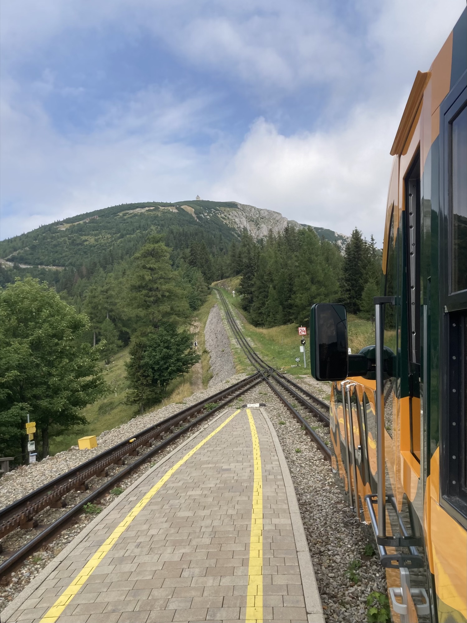 Blick zum Gipfel des Schneebergs vom Bahnsteig der Haltestelle Baumgartner, die eingleisige Strecke teilt sich hier in zwei Gleise, auf denen deutlich die Vorrichtung der Rahnradbahn erkennbar ist